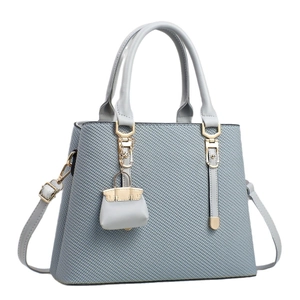Minimalist light blue tote bag with woven texture and gold hardware on white background