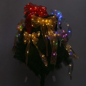 Close-up of glowing LED Christmas ribbon bows with colorful lights on dark tree