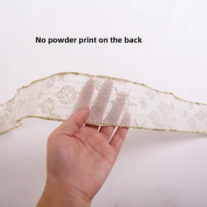 Detail of white mesh Christmas ribbon with gold glitter edges and festive prints