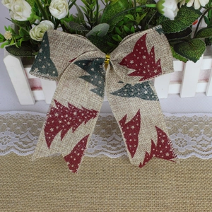 Detail of Christmas burlap bow with red and green tree print on woven texture