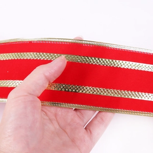 Close-up of red velvet Christmas ribbon with gold embossed stripes and metallic edges