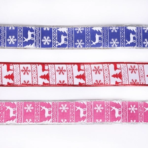 Close-up of printed Christmas ribbons with snowflake and reindeer patterns on faux burlap