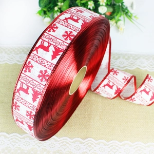 Macro detail of red Christmas ribbon featuring printed reindeer, snowflakes and trees