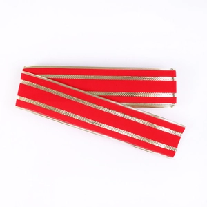 Close-up of red velvet Christmas ribbon with metallic gold stripes for festive decor
