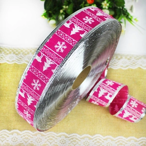 Detail of rose red Christmas ribbon roll with white reindeer and snowflake prints