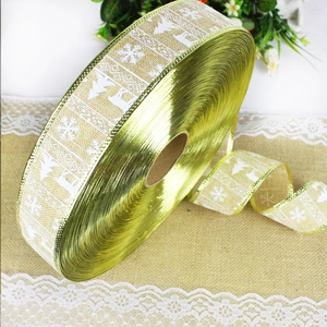Close-up of Christmas burlap ribbon roll with white reindeer patterns and gold wired edges