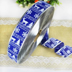 Close-up of blue Christmas ribbon with white reindeer and snowflake patterns and silver edges