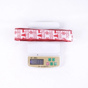 Christmas ribbon with elk and snowflake patterns on scale showing 117g weight