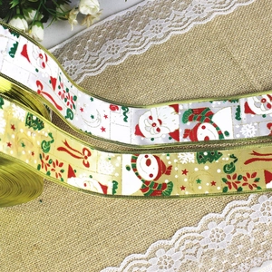 Detailed view of Christmas ribbon with snowman and santa prints on gold wired edge fabric