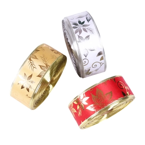 Close-up of three rolls of 10m satin ribbons with metallic floral prints for Christmas decor