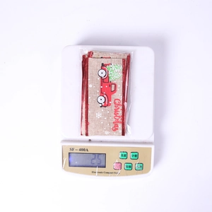 Top view of a Christmas truck ribbon bow being weighed on a digital scale for accuracy