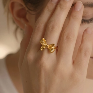 Elegant gold PVD plated stainless steel bow ring with vintage texture on female finger
