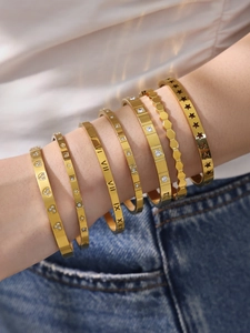 Detail of layered gold Roman numeral bracelets with zircon stones on female model
