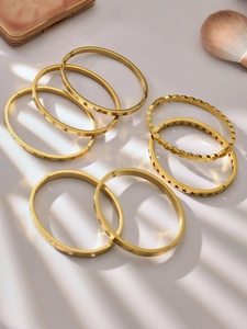 Detailed stack of gold plated stainless steel bangles with micro-pave zircons and engravings