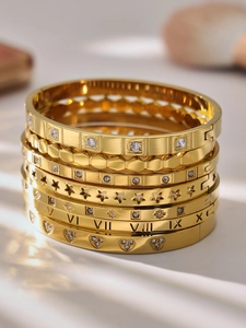 Macro shot of 18k gold-plated stackable bracelets with Roman numerals and zircon stones