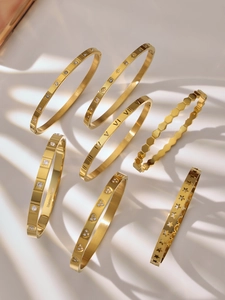 Macro detail of seven-piece 18K gold-plated stainless steel bangles with star and heart patterns