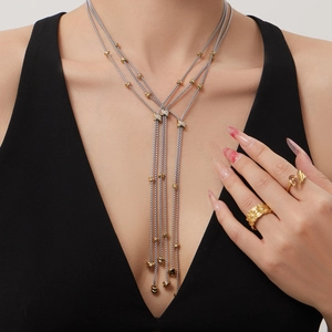 Collier à pampilles bicolore multicouche avec bagues en or texturées sur un mannequin