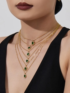 Detailed view of layered 18k gold necklaces featuring multiple green zircon pendants