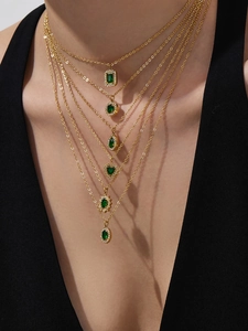 Close-up of layered necklaces with emerald green pendants and micro zircon accents