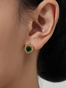 Close-up of vintage heart stud earrings with green center stone and cubic zirconia inlay