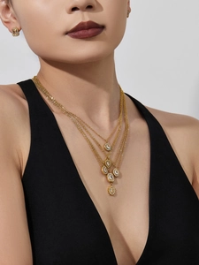 Detail of layered gold necklaces with zircon heart and geometric pendants on model