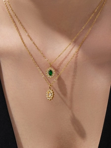 Close-up of double-layer gold necklace with green and clear flower gemstone pendants