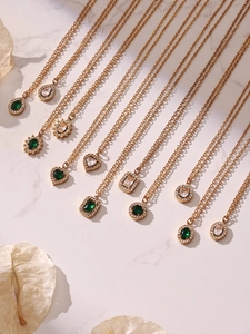 Detailed flat lay of 18k gold plated necklaces featuring emerald and zircon pendants