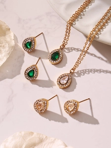 Detail view of water drop zirconia earrings and necklaces on white marble surface