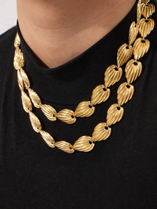 Close-up of vintage golden tiered necklace with textured fan-shaped charms and metallic links
