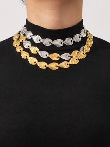 Detailed layered necklace view showing gold and silver textured links on a black turtleneck