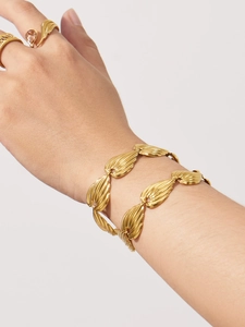 Close-up of gold chain bracelet with radial textured leaf links and vintage style rings