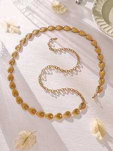 Detail of adjustable gold stainless steel waist chain with leaf textured metal charms