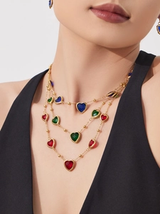 Gros plan du collier doré multi-rangs avec pierres précieuses en forme de cœur coloré