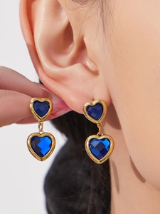 Vue macro de boucles d'oreilles cœur en verre bleu avec monture dorée à l'or 18 carats