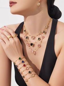 Gros plan de colliers avec cœurs en pierres et bracelets dorés portés par un mannequin