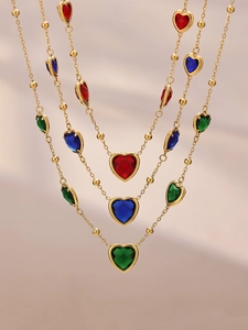 Détail des pendentifs cœur en cristal sur colliers de perles plaqués or en trois couleurs