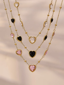 Détail du collier plaqué or 18k avec pendentifs en forme de cœur en verre rose et noir