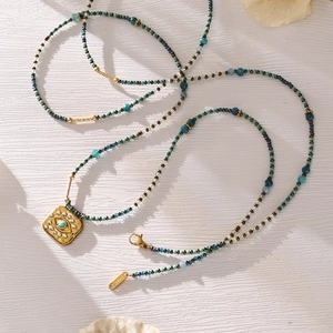 Evil Eye pendant necklace with turquoise beads and gold accents on a white background