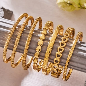 Minimalist gold heart and geometric stainless steel bracelets on a decorative column