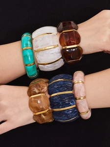 Detailed view of layered colorful resin bracelets with gold spacers on model wrist