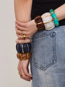 Detail of vintage resin bangles with carved textures and gold-tone heart rings on a model