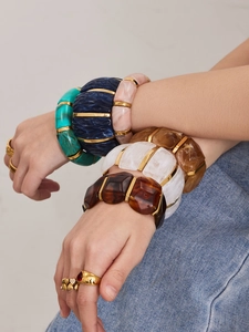 Detail of stacked vintage resin bracelets with gold spacers and ruby-accented rings