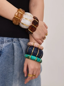 Dettaglio di bracciali elastici in resina colorata con distanziatori in metallo dorato
