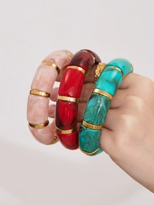 Close-up of geometric resin bamboo bracelets with marble texture and gold ring links