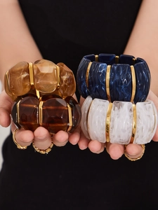 Detailed close-up of resin cuff bracelets with 18k gold accents in amber and marble blue