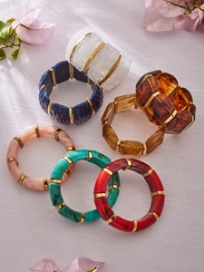 Group of colorful resin elastic bracelets with golden spacer beads on a wooden surface