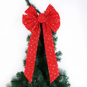 Detail view of red velvet Christmas bow with gold stars on festive green tree