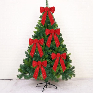 Detail of five red velvet Christmas bows with gold stars on a green tree branch