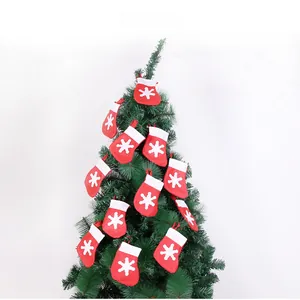 Detailed view of red Christmas socks with white snowflake hanging on green tree branches