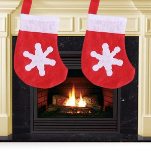 Set of two red Christmas stockings with white snowflake patterns hanging by a fireplace
